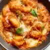 Delicious baked gnocchi topped with cheese and herbs in a baking dish