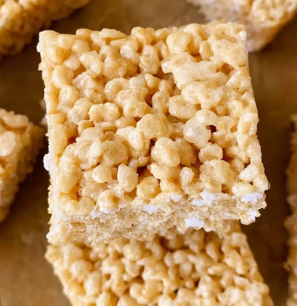 Brown butter rice krispies treats on a white plate, drizzled with caramel.