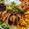 A colorful chicken burrito bowl filled with vibrant vegetables and toppings.