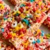 Colorful Fruity Pebbles Rice Krispie Treats stacked on a plate