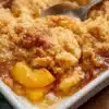 Delicious homemade Peach Cobbler in a baking dish, topped with golden crust.