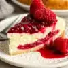 Delicious slice of Raspberry Cheesecake topped with fresh raspberries and cream.