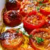 Deliciously roasted tomatoes garnished with herbs, showcasing vibrant colors and textures.