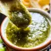 Freshly made Salsa Verde in a bowl with cilantro and lime wedges