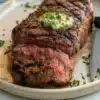 Delicious steak topped with savory herb butter on a plate