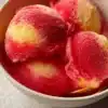 Bowl of vibrant strawberry pineapple sorbet with fresh fruits on top.